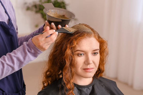Βαφή των μαλλιών της νεαρής γυναίκας με χέννα στο σαλόνι ομορφιάς - Φωτογραφία, εικόνα