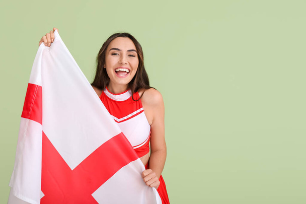 Beautiful cheerleader with the flag of England on color background - Фото, изображение