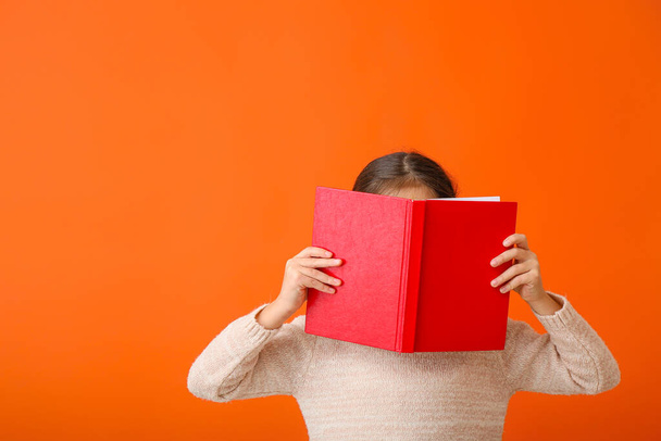 Χαριτωμένο κοριτσάκι με το βιβλίο στο φόντο χρώμα - Φωτογραφία, εικόνα