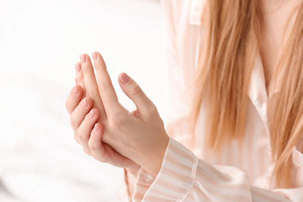 jonge vrouw aanbrengen crème op haar handen, close-up - Foto, afbeelding