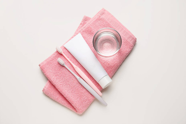zubní kartáčky, pasta, sklenice vody a ručník na bílém pozadí - Fotografie, Obrázek