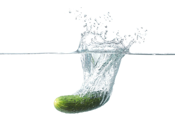 Falling of fresh cucumber into water against white background - Foto, Imagen