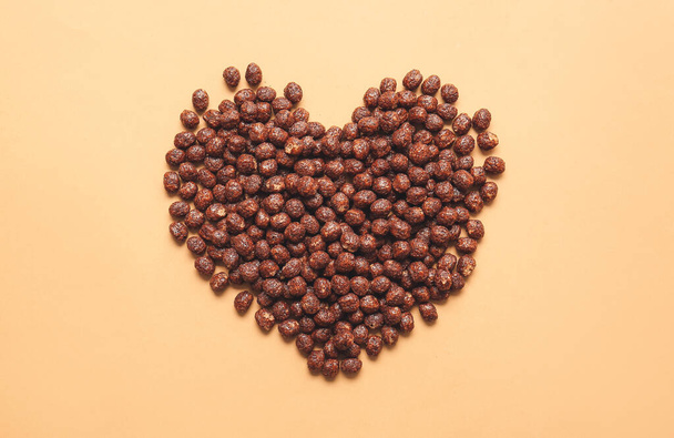 Heart shape made of chocolate corn balls on color background - Photo, image