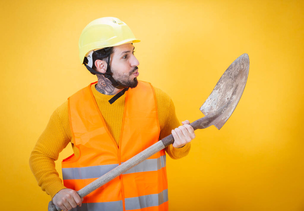 δυνατός και ψηλός όμορφος εργάτης με κίτρινο φόντο - Φωτογραφία, εικόνα
