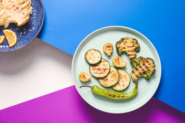 Plates with tasty grilled vegetables on color background - 写真・画像