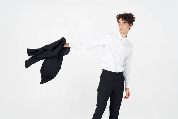 muodikas kaveri paita ja housut takki kädessään kevyellä taustalla rajattu näkymä malli Kopioi tilaa - Valokuva, kuva