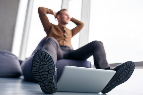 Le pied d'un homme dans les chaussures est près de l'ordinateur portable. L'homme veut marcher sur son ordinateur portable - Photo, image