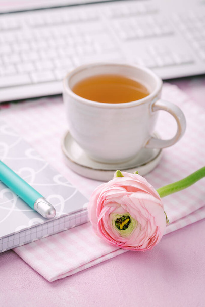 Thuiskantoor met kopje thee, bloem, toetsenborden en schrijfbenodigdheden - Foto, afbeelding