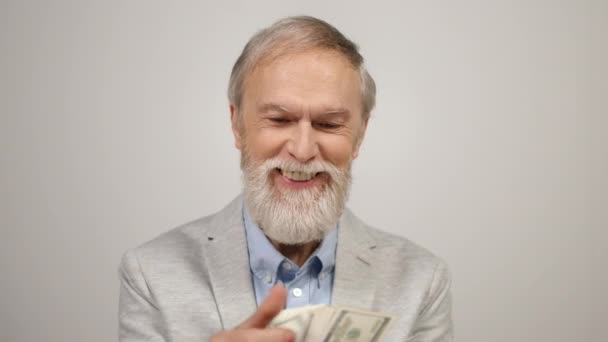 Feliz anciano contando dinero en el interior. Hombre rico sosteniendo dólares en estudio moderno. - Metraje, vídeo