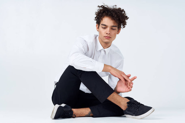 tiener in sneakers, zwarte broek en een wit shirt in een heldere kamer in volle groei - Foto, afbeelding