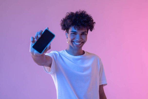 Headshot of curly-haired smiling guy with a smartphone - Foto, Imagem