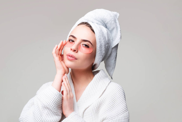 Portrait of beauty woman with eye patches showing an effect of perfect skin. Under eye masks for puffiness, wrinkles, dark circles. Sexy woman in white bathrobe applying eye patches. - Photo, Image