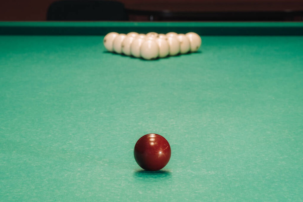 They play pool on a green table.The balls are placed in a triangle on the table - Foto, afbeelding