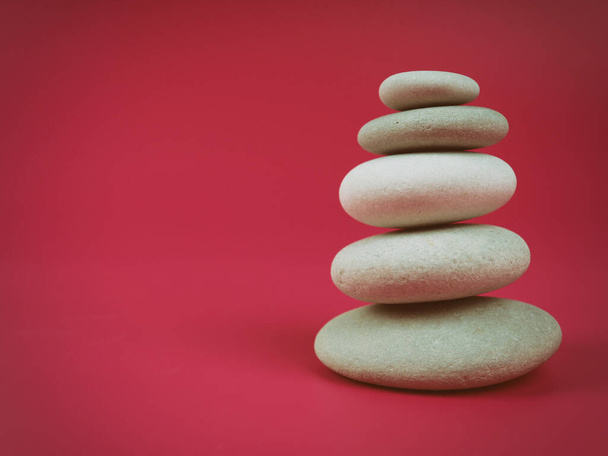 A stack of white zen stones on a pink background, minimalism. - Photo, Image