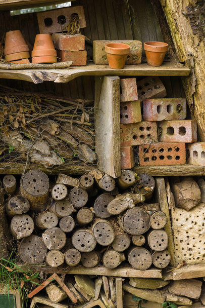 Owad hotel lub dom owadów wykonane ze starych kłód cegieł i glinianych garnków w celu zapewnienia schronienia i gniazdowania lub hibernacji dla os pszczół i innych bezkręgowców - Zdjęcie, obraz