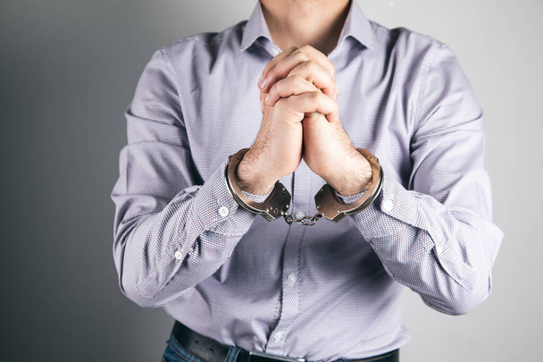 Mann betet in Handschellen vor grauem Hintergrund - Foto, Bild