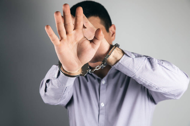 Человек в наручниках закрывает лицо - Фото, изображение