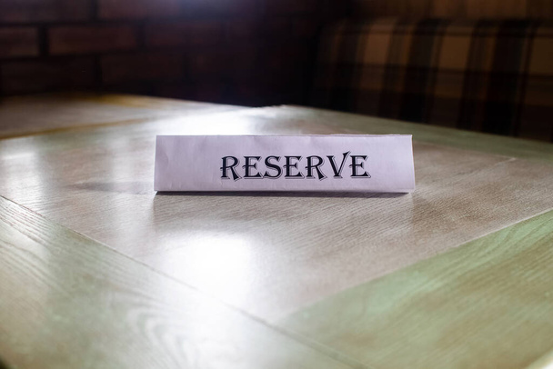 Le vol autour de la plaque est réservé, qui se trouve sur la table en bois dans le restaurant. Réservation d'une place dans le café. Réservation de sièges. Réserver une table dans l'institution à l'avance. - Photo, image