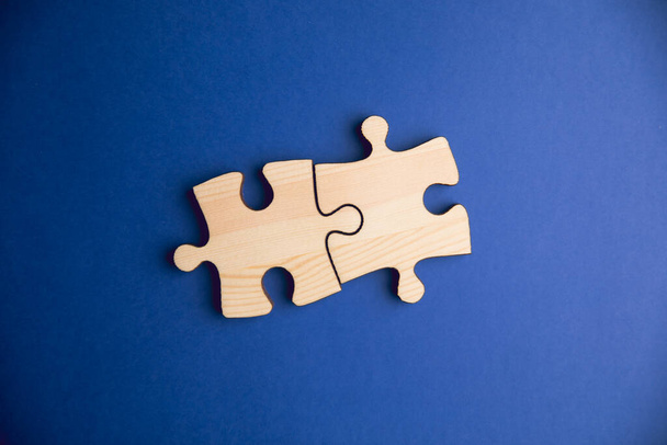 two pieces of wood jigsaw puzzle on a blue background - Foto, Bild