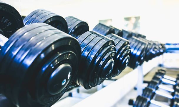 Heavy dumbbells lying in the raw in the gym. Fitness sport motivation. Happy healthy lifestyle living. Exercises with bars weights. - Foto, Imagen