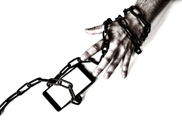 Rusty chains around the smartphone with hand. Addicted to modern technologies. - Photo, Image