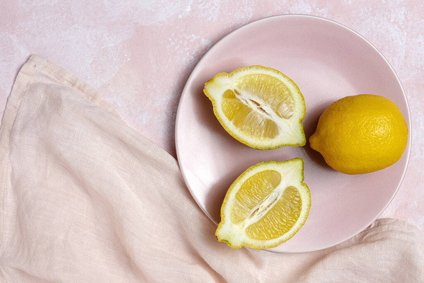 Fresh lemons with green mint leaves on pink background from above. Flat lay - Foto, afbeelding