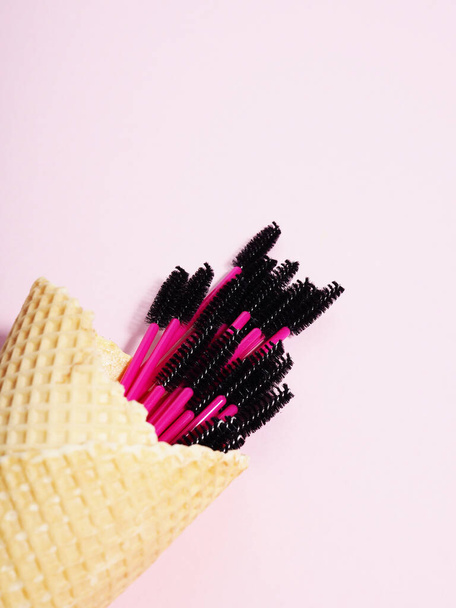 Kreative Wimpernbürsten in Eistüten auf rosa Hintergrund, Wimpernverlängerungen. - Foto, Bild