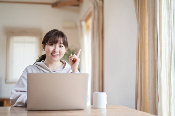 リビングルームで笑顔でコンピュータを操作するアジアの女性 - 写真・画像