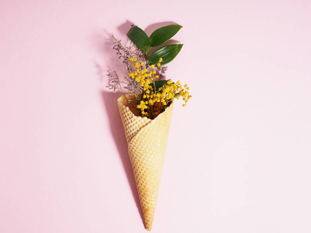 Bouquet of dried flowers in a waffle cup from ice cream, cone, on a pink background, minimalism. - Photo, Image