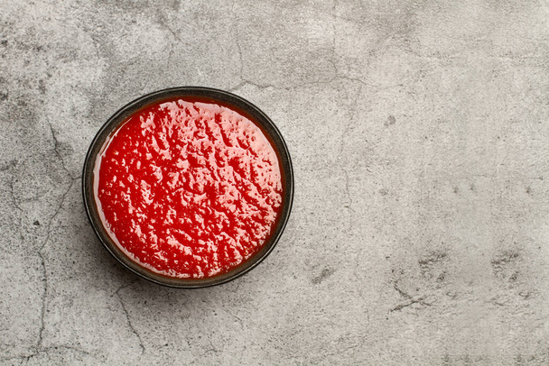 Tomato sauce in a black bowl on a marble table in a top view - Foto, imagen