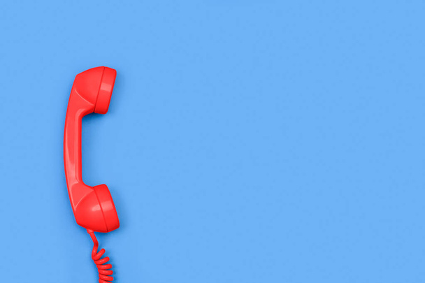 Un viejo receptor de teléfono rojo sobre un fondo azul con espacio para copiar - Foto, Imagen