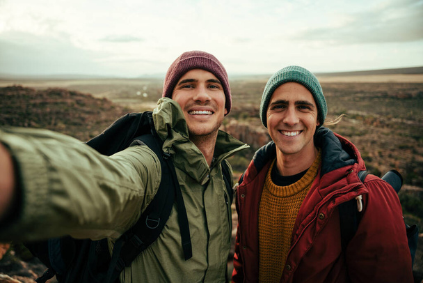 Caucasian male friend taking selfie with cellular device smiling while on outdoor hike - Foto, afbeelding
