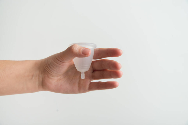 hand is holding menstrual cup on white background - Zdjęcie, obraz