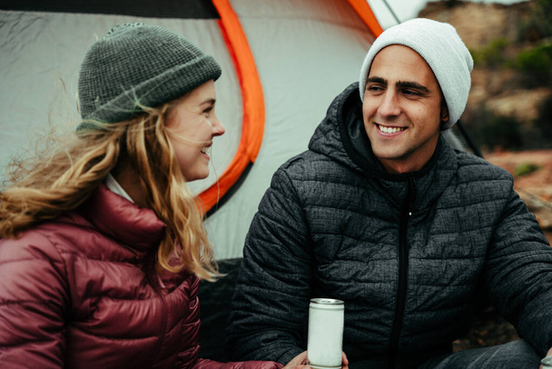 Caucasian couple smiling at each other chatting while camping in mountain - Photo, Image
