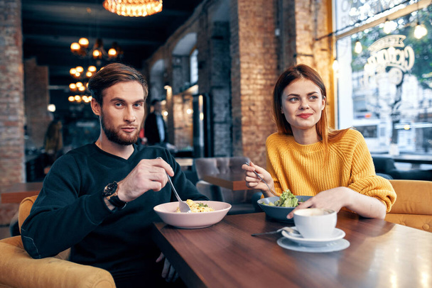 веселая молодая пара, сидящая в ресторане и питающаяся - Фото, изображение