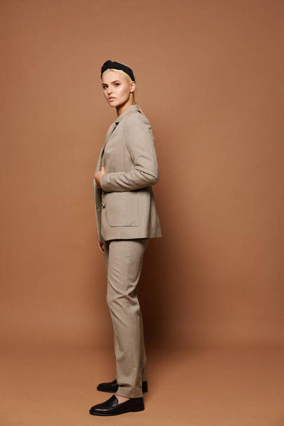 A young woman wearing official-style clothes isolated on a beige background. Model blond girl in modish suit isolated at the background with copy space - Photo, Image