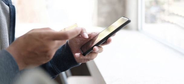 Online fizetés, Mans kéz kezében egy hitelkártya és használata okostelefon az online vásárlás - Fotó, kép