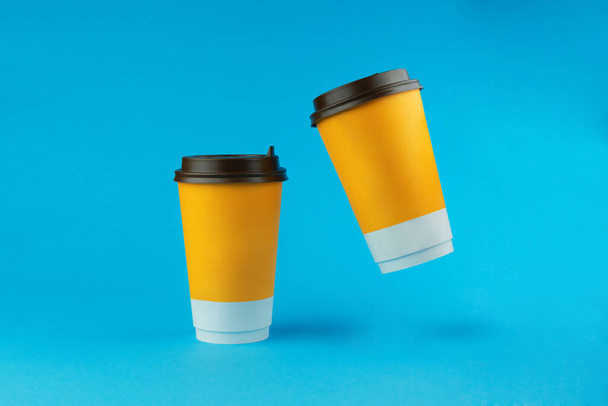 Two paper coffee cups on a blue background - Фото, зображення