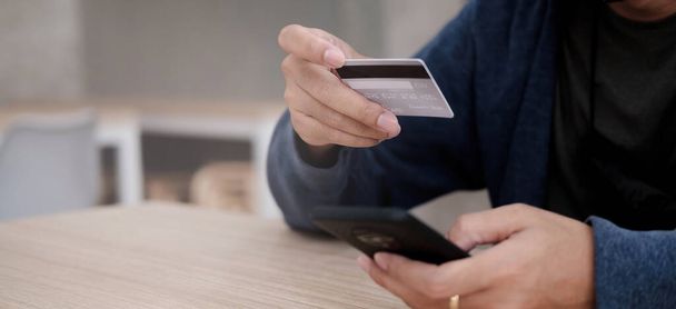 Paiement en ligne, Mans mains tenant une carte de crédit et utilisant un téléphone intelligent pour les achats en ligne - Photo, image