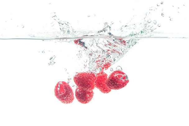 Raspberries splashing in water on white - Foto, imagen