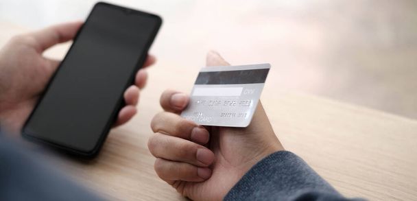 Online payment,Mans hands holding a credit card and using smart phone for online shopping - Photo, image