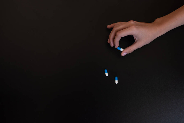the girl holds a pill with her fingers. Copy space - Photo, Image