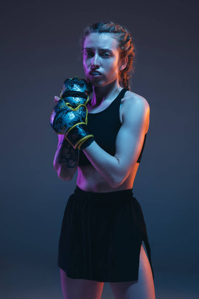 Beyaz kadın MMA dövüşçüsü mavi arka planda, neon ışıkta yalnız poz veriyor. - Fotoğraf, Görsel