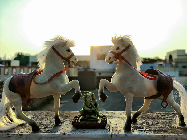 Фотографія двох білих кольорових пластмасових конячих іграшок зберігається на підлозі під яскравим сонячним світлом на тьмяному тлі в Gulbarga Karnataka India. - Фото, зображення