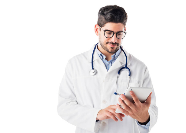 Shot of male doctor using digital tablet while standing at isolated white background. Copy space.  - Фото, зображення