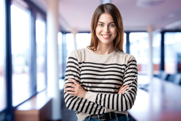 Portrait of happy young businesswoman standing with arms crossed in the conference room.  - Photo, image