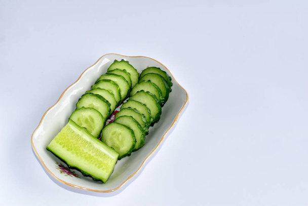 Eine Nahaufnahme von zwei Reihen aufgeschnittener grüner Gurken auf einem Teller. - Foto, Bild