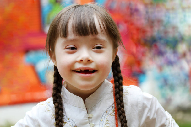 Portrét holčičky usmívající se na pozadí barevné stěny - Fotografie, Obrázek