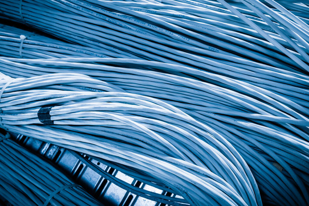 подробности большого количества кабелей Ethernet, связанных между собой соединительными стойками внутри серверной - Фото, изображение