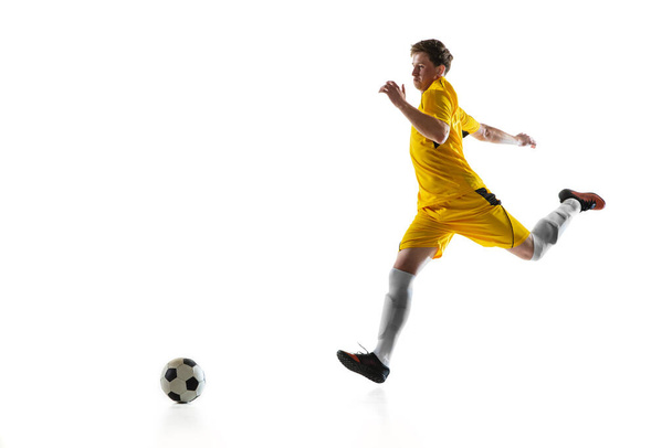 Junger Mann, männlicher Fußballspieler trainiert isoliert auf weißem Hintergrund. - Foto, Bild
